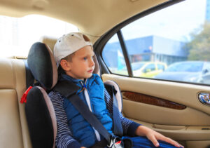 Baby boy sitting in child car seat in car.