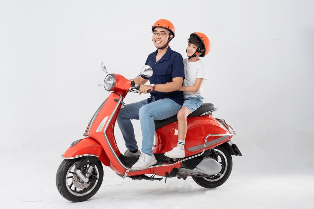 father and son wearing helmets and riding motorbikes